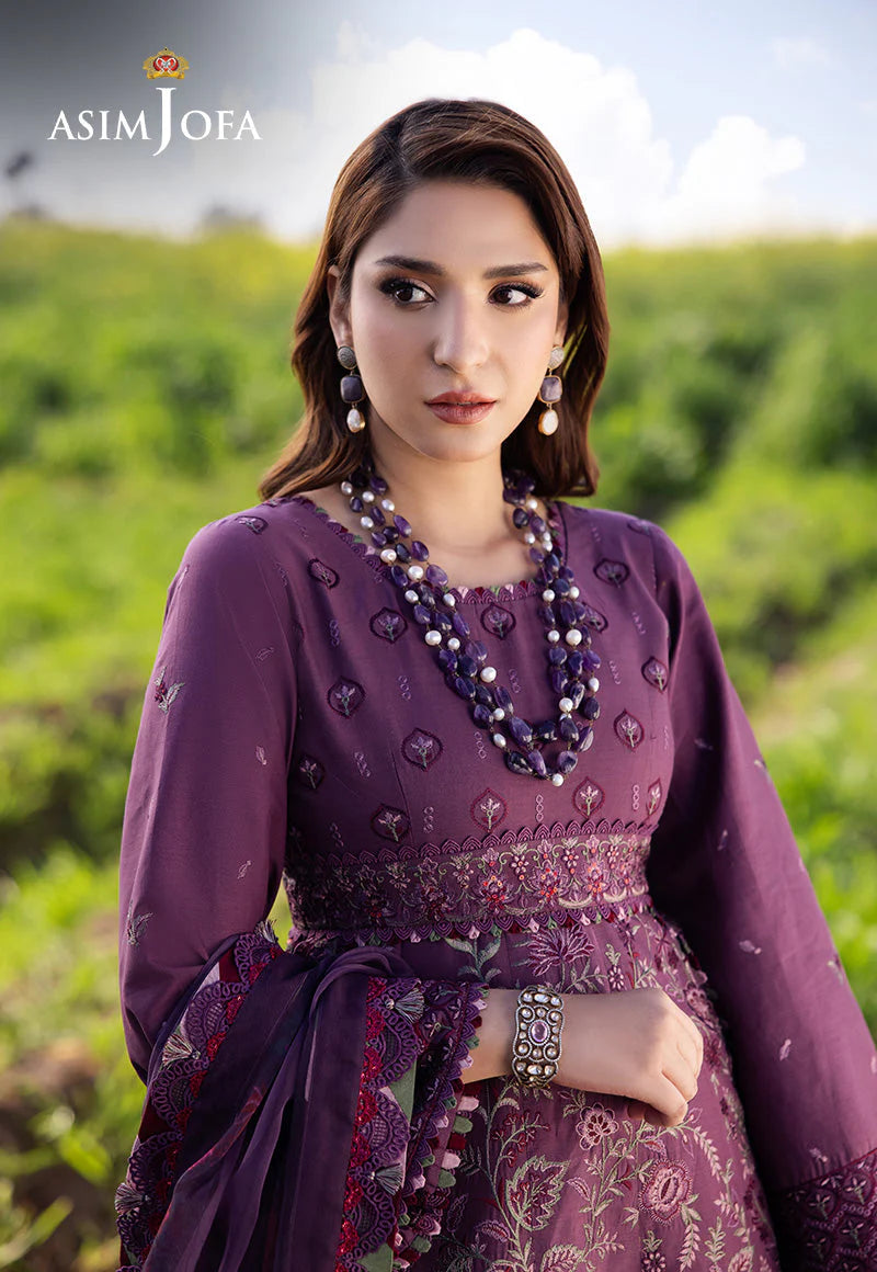 Woman wearing a purple traditional outfit with jewelry in a green outdoor setting, featuring the Asim Jofa brand.