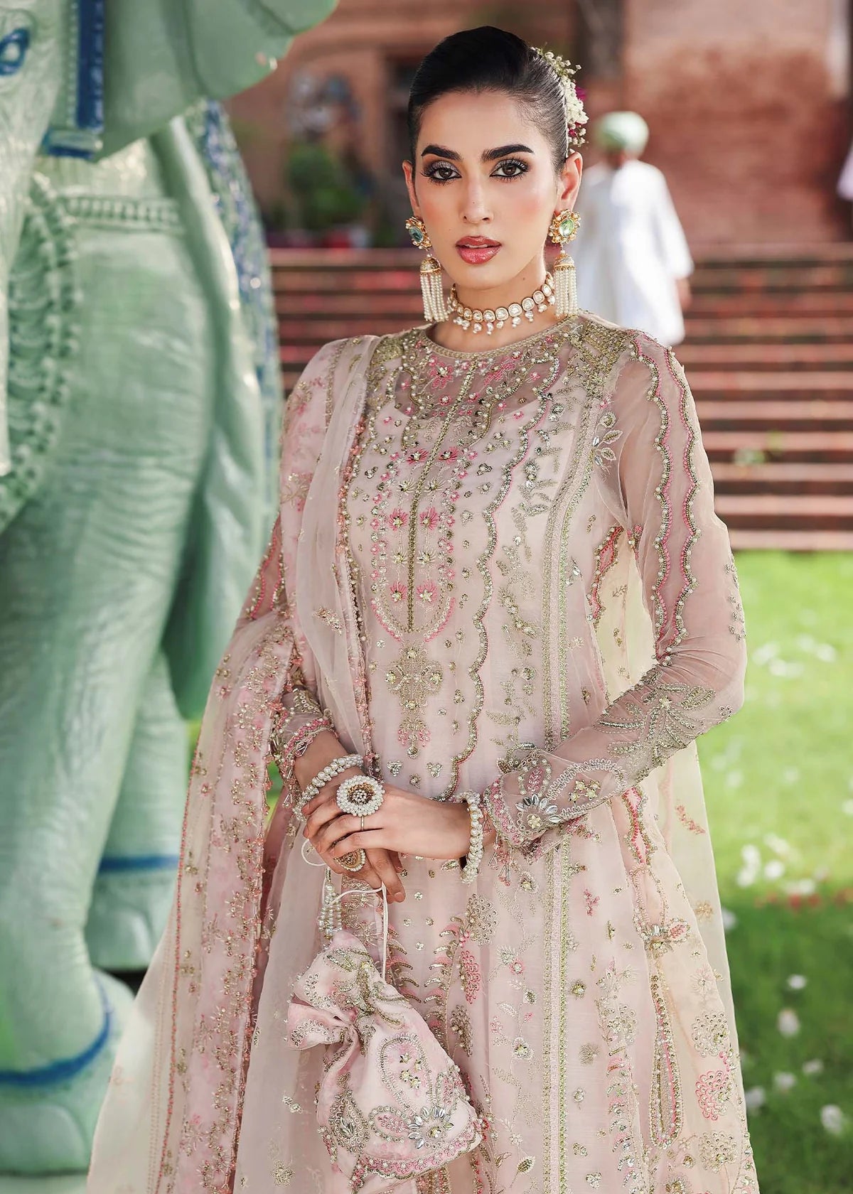 Woman in traditional pink embroidered outfit with elephant in the background