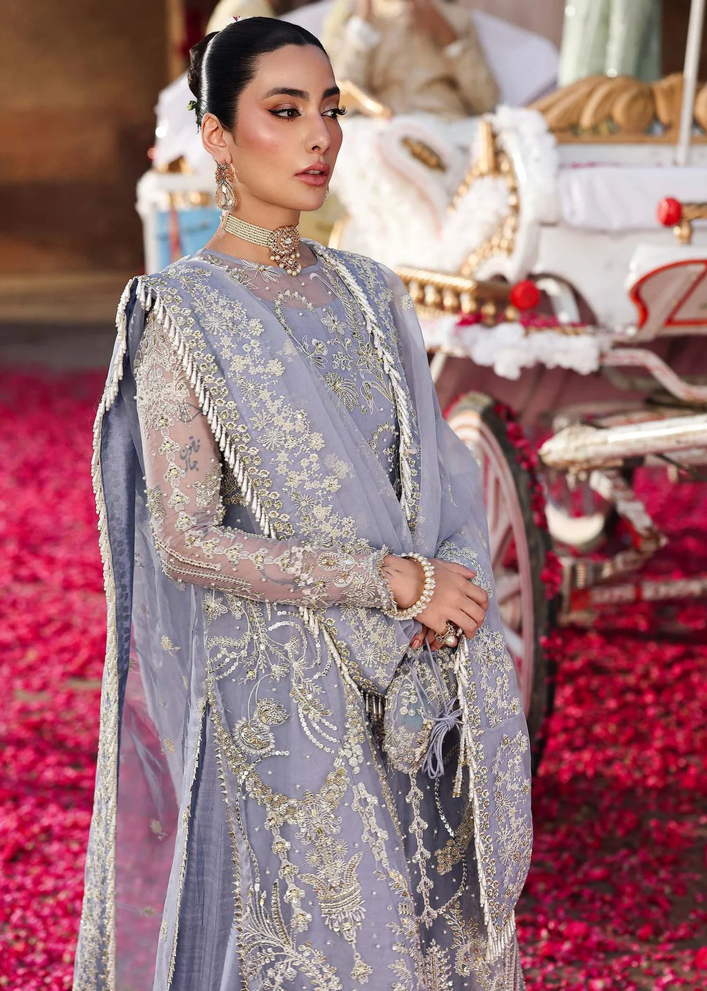 Woman in a light blue embroidered traditional outfit with a red and gold background
