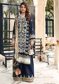 A woman models a traditional three-piece navy blue salwar kameez suit with intricate silver and gold embroidery, paired with a beige dupatta, in an outdoor courtyard setting.