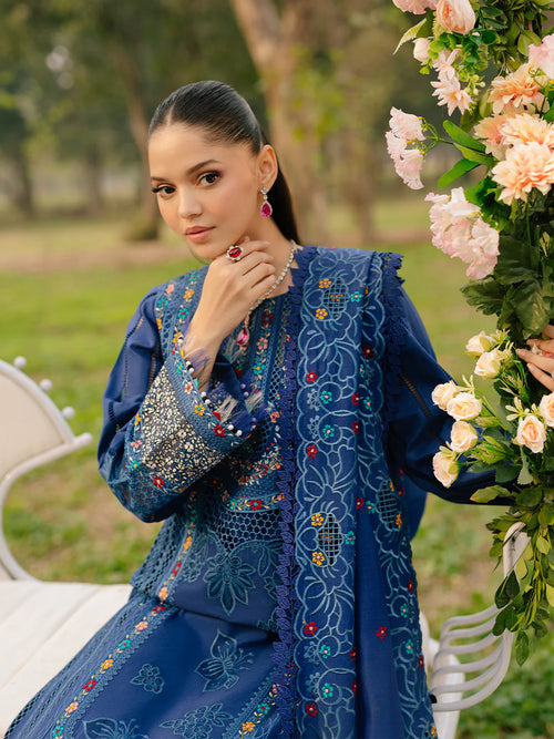 Woman in a blue embroidered outfit holding flowers outdoors