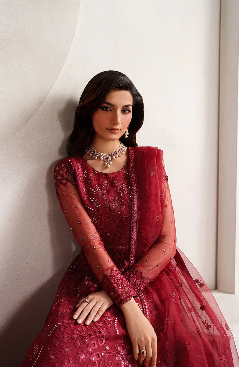 Woman wearing a red embroidered traditional outfit against a neutral background