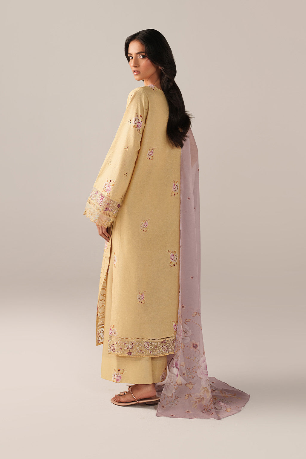 Woman wearing a light yellow embroidered outfit with a matching dupatta on a plain background