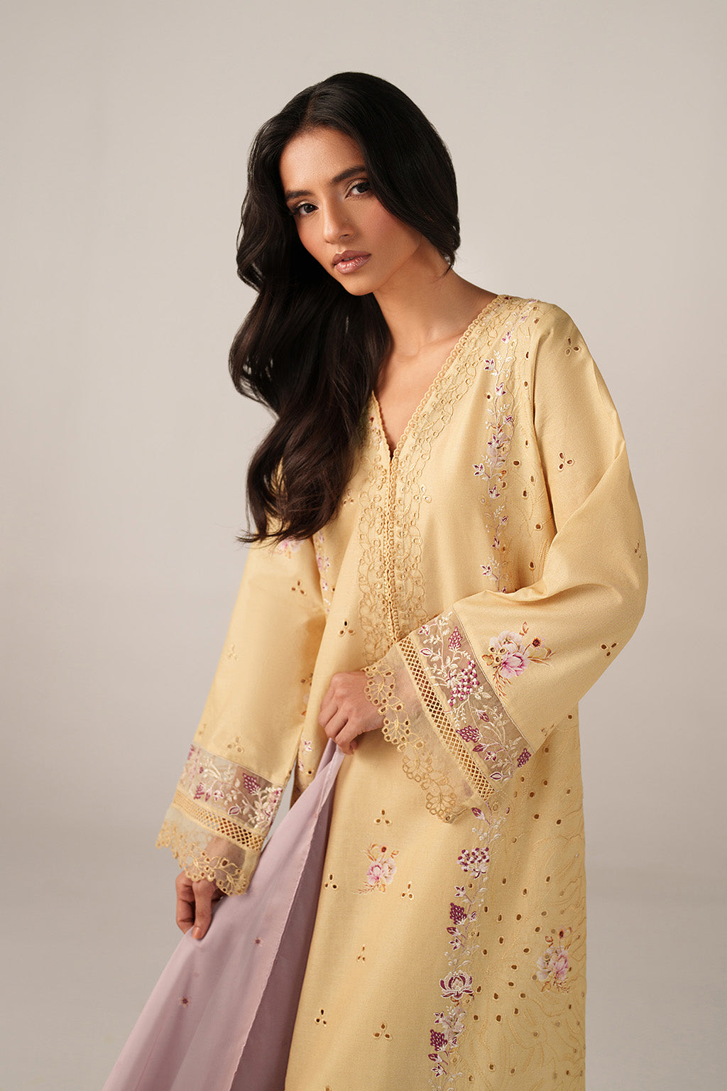 Woman wearing a yellow embroidered dress with a plain background
