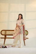 Woman in a traditional outfit with a floral dupatta standing in front of a wooden bench.