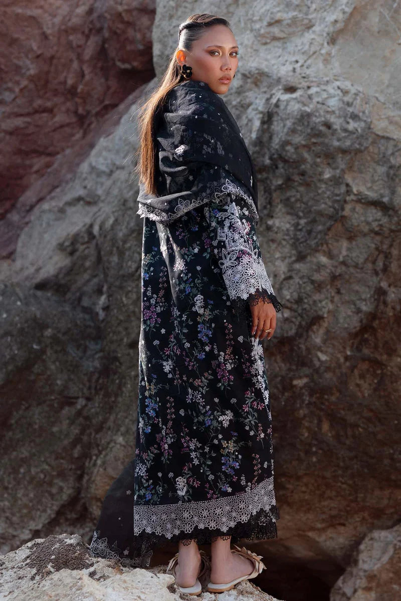 Woman in a long, dark floral dress standing against a rocky background