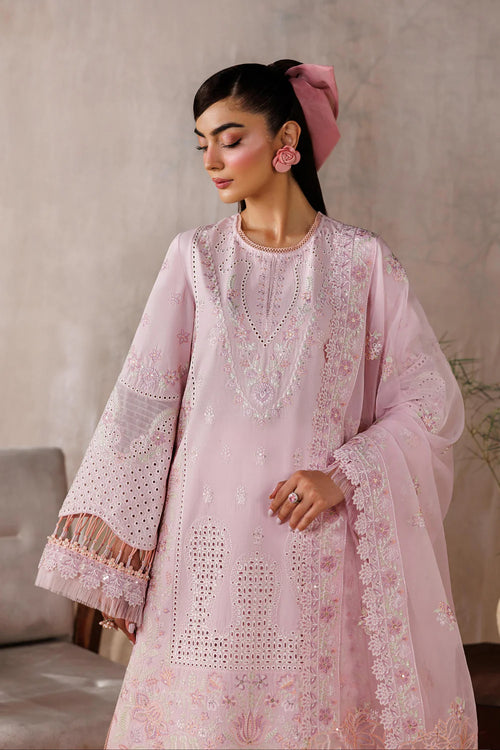 Woman wearing a light pink embroidered traditional outfit against a neutral background