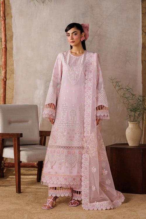 Woman wearing a pink embroidered traditional outfit in a room with a neutral background