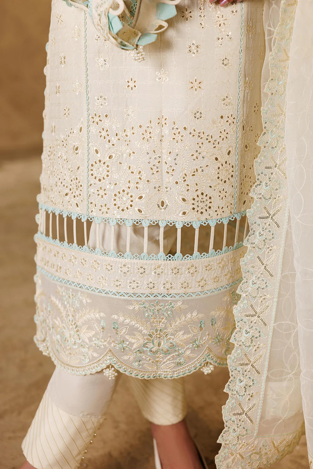 Close-up of a cream-colored embroidered traditional outfit with a belt.