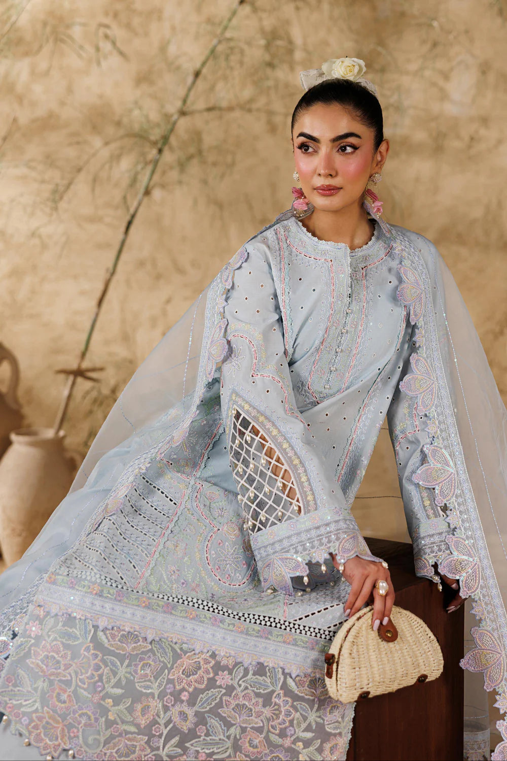 Woman in a light blue embroidered traditional outfit with a beige background