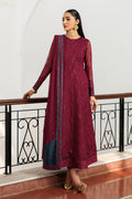 Woman in a maroon traditional outfit with a blue border standing indoors.