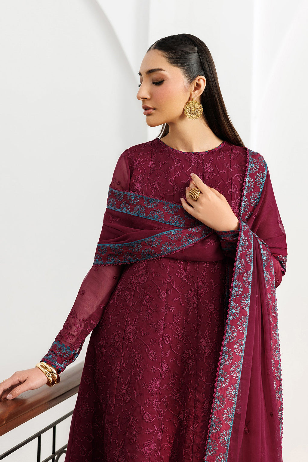 Woman wearing a maroon traditional outfit with a matching dupatta on a white background