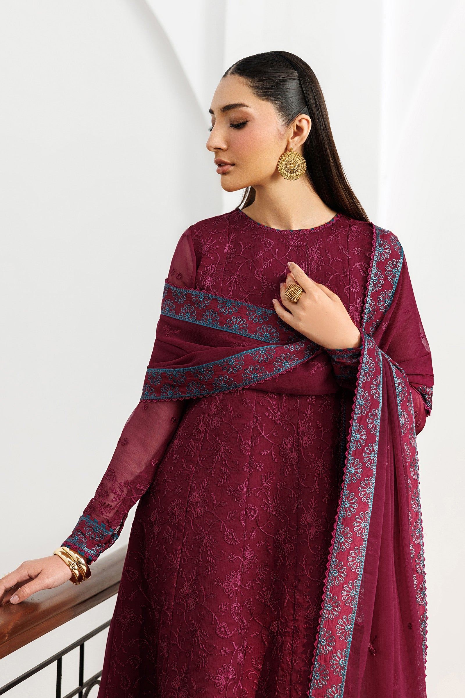 Woman wearing a maroon traditional outfit with a matching dupatta on a white background