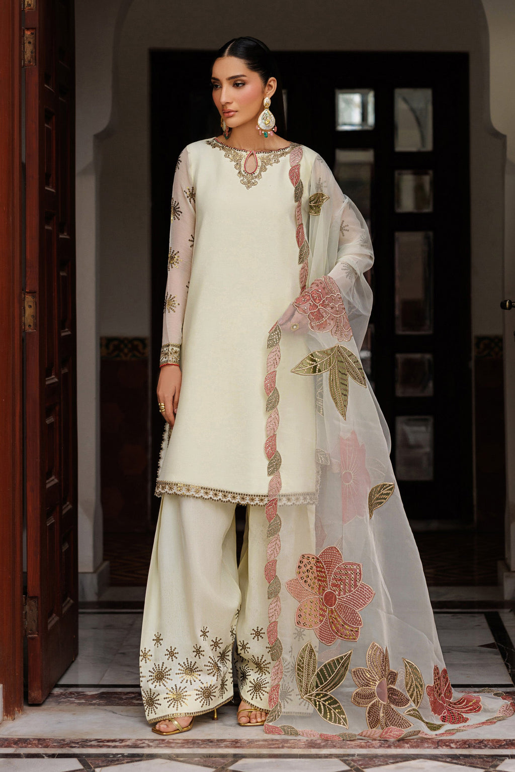 Woman wearing a traditional outfit with floral embroidery in an indoor setting