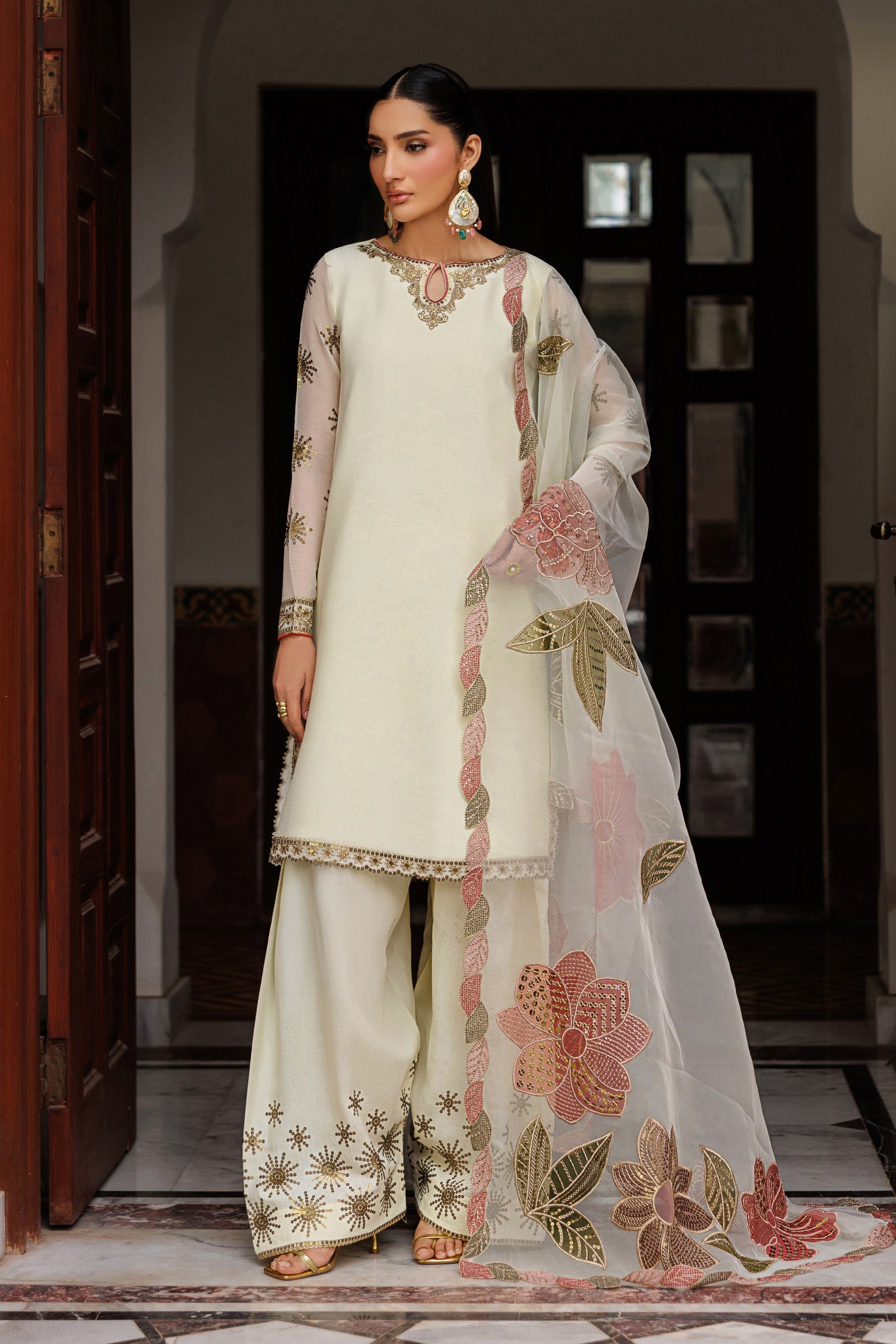 Woman wearing a traditional outfit with floral embroidery in an indoor setting