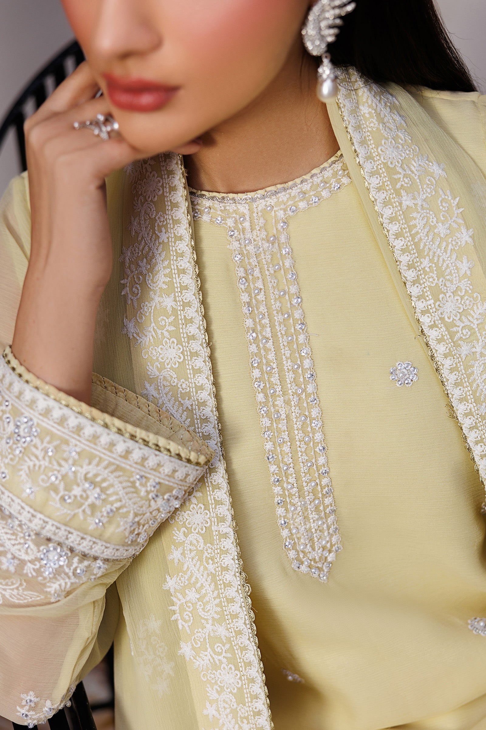 Close-up of a light yellow traditional outfit with intricate white embroidery.