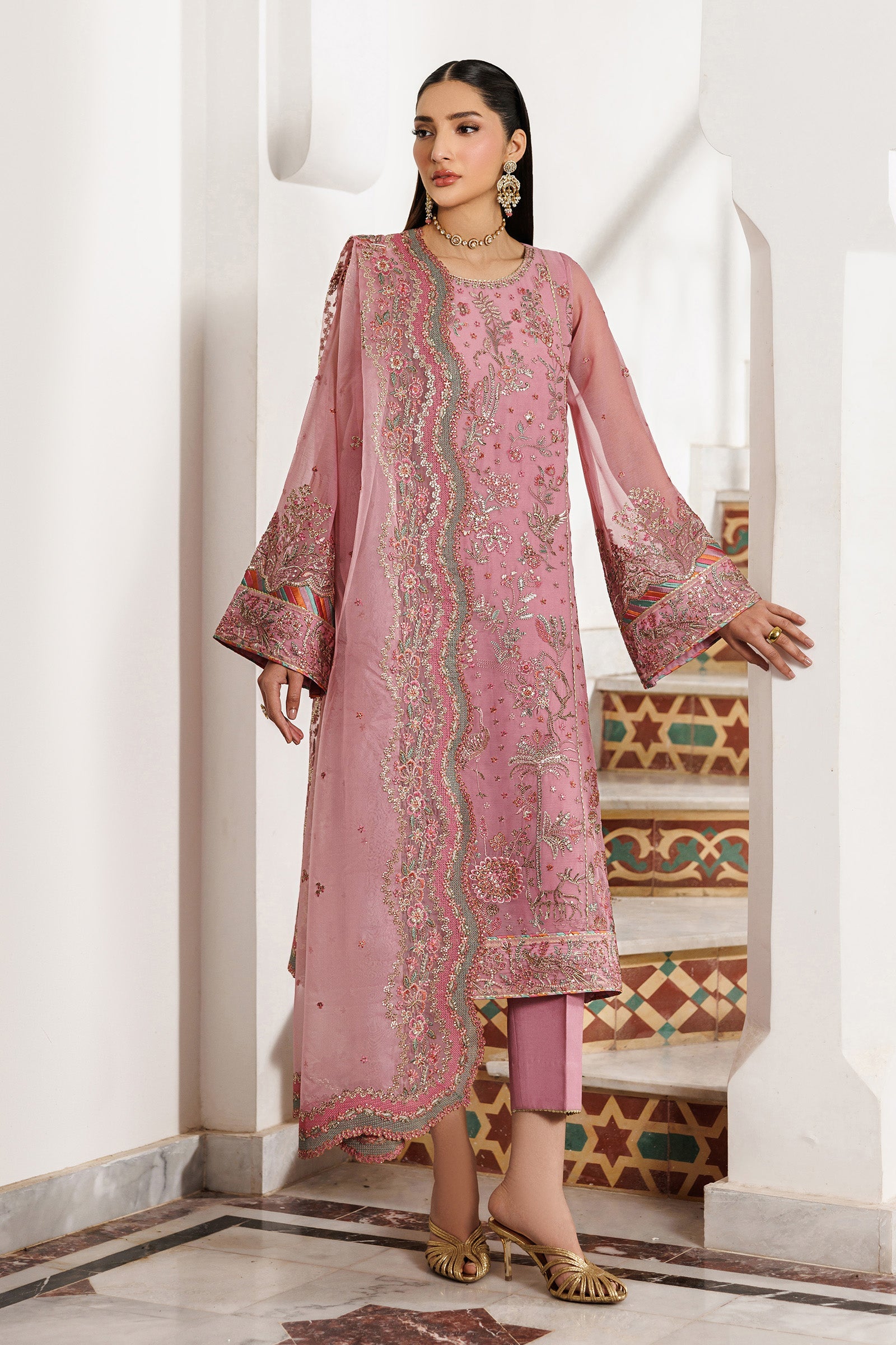 Woman wearing a pink embroidered traditional outfit in an ornate interior setting