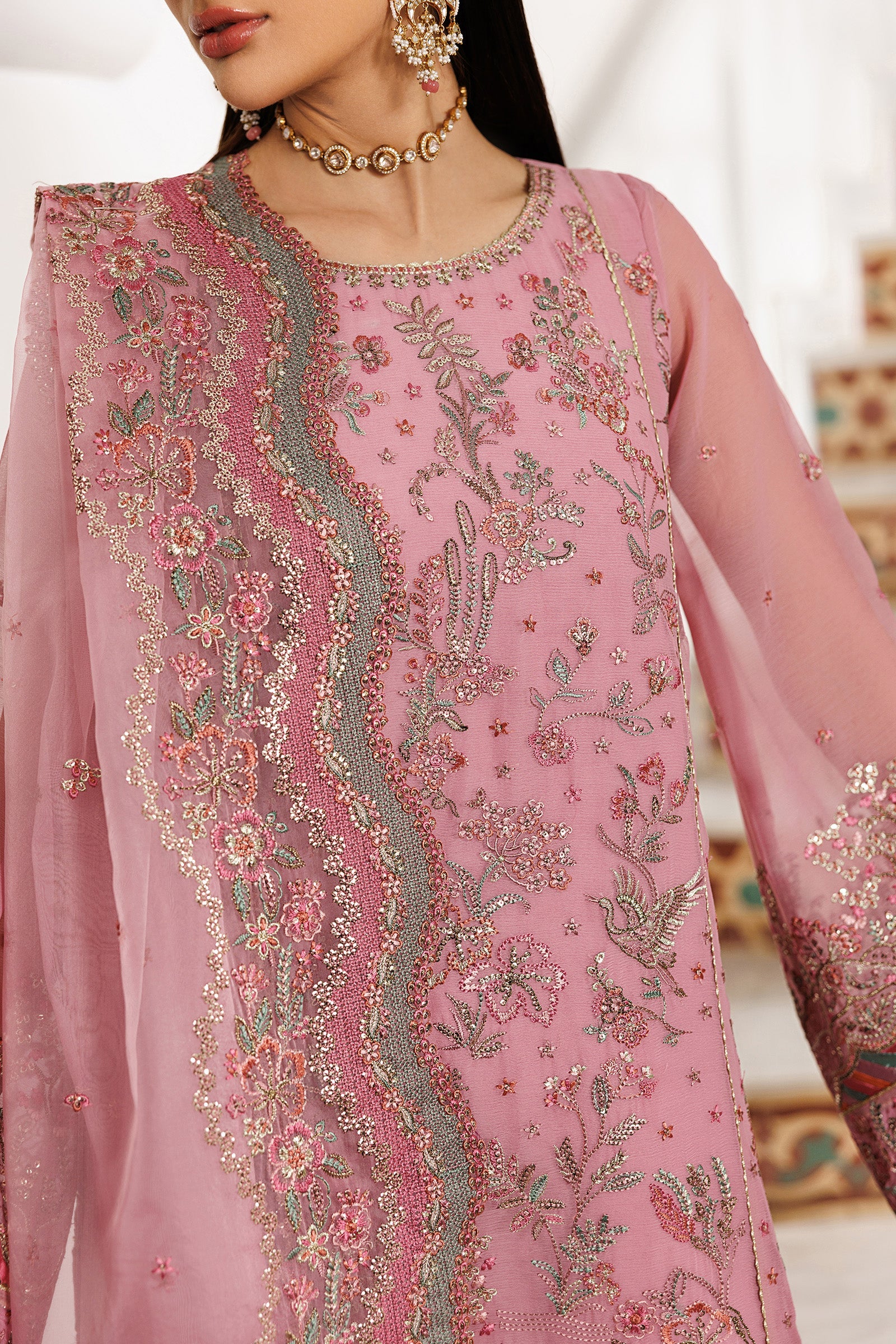 Pink embroidered traditional outfit with intricate designs on a blurred background