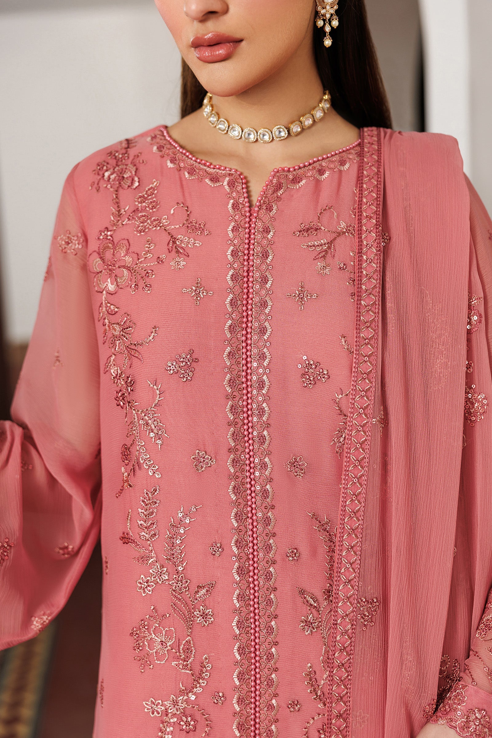 Close-up of a pink embroidered traditional outfit with intricate patterns.