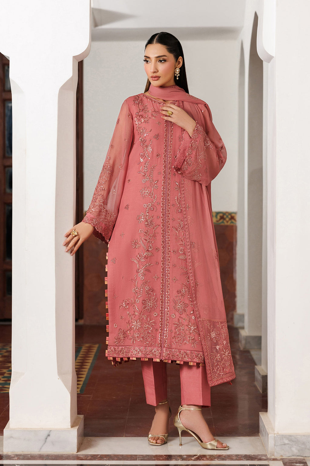 Woman wearing a pink embroidered outfit in an elegant interior setting