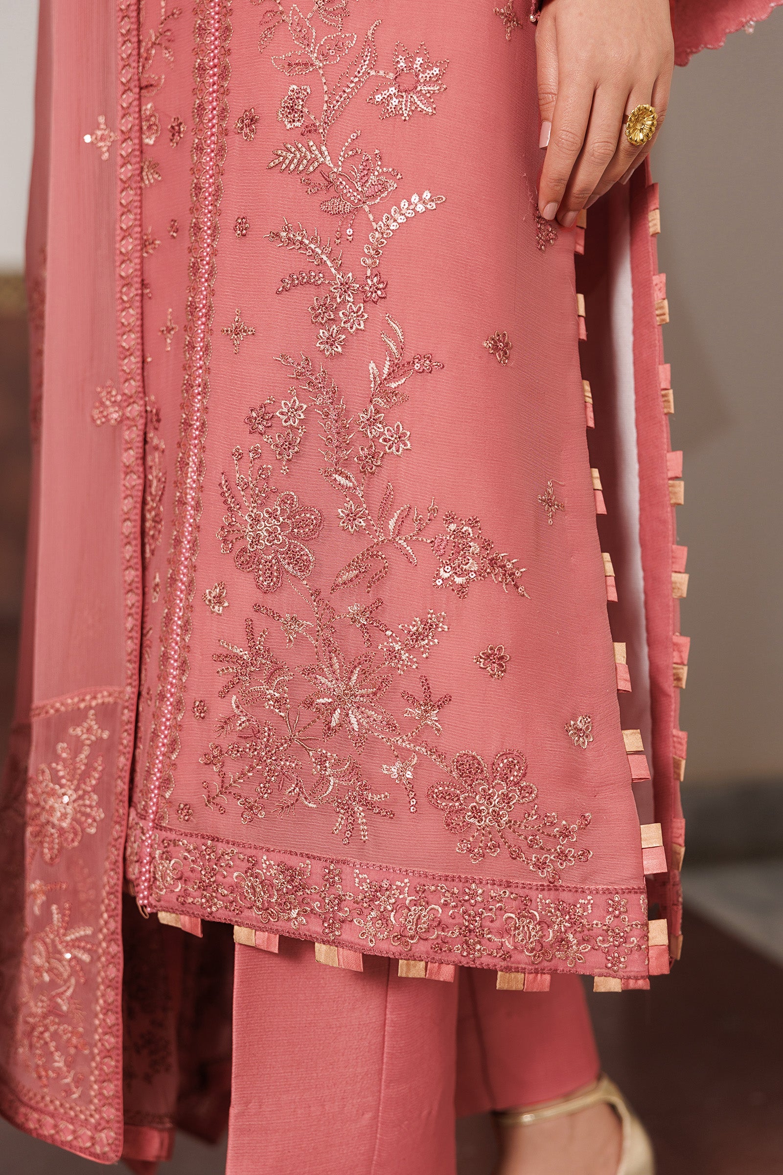 Pink embroidered traditional outfit with floral patterns on a plain background