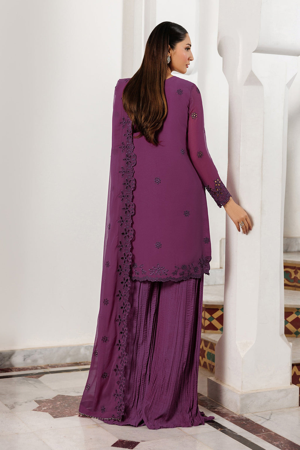Woman wearing a purple traditional outfit with a white architectural background