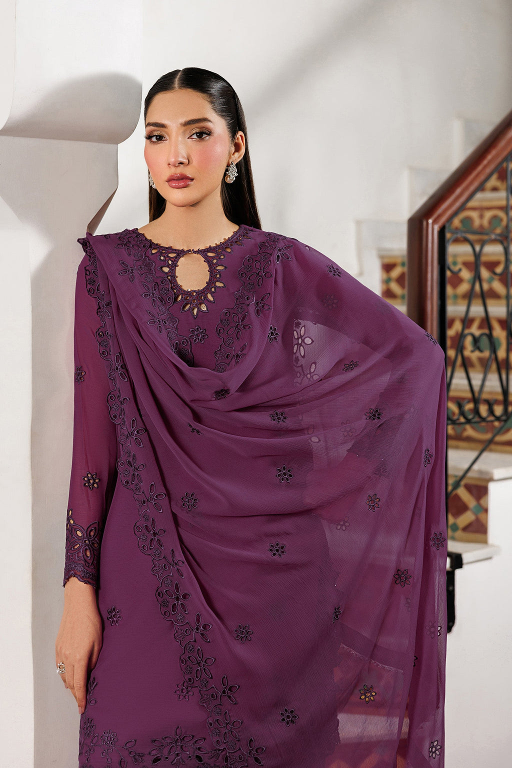 Woman wearing a purple embroidered saree in an indoor setting