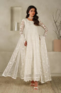 Woman wearing a white embroidered dress in an indoor setting