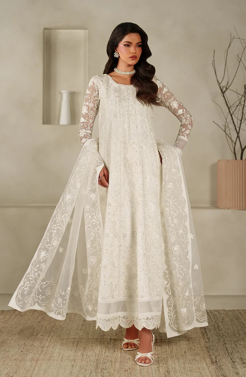 Woman wearing a white embroidered dress in an indoor setting