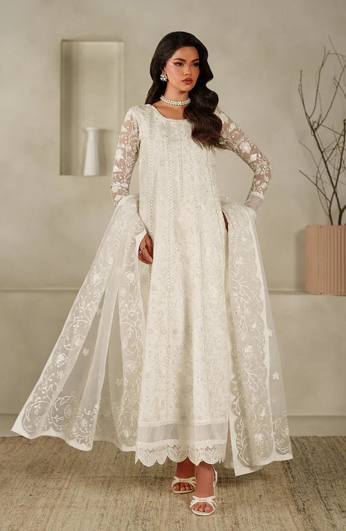 Woman wearing a white embroidered dress in an indoor setting