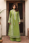 Woman wearing a green embroidered traditional outfit standing in front of a wooden door.
