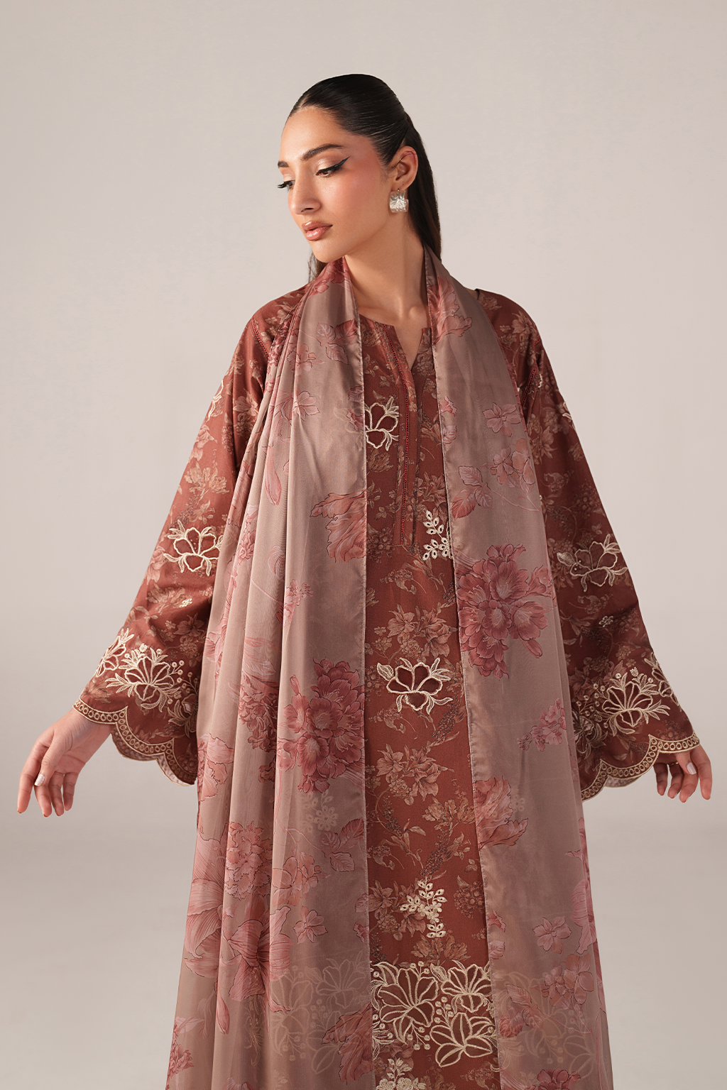 Woman wearing a floral embroidered dress with a matching dupatta on a plain background