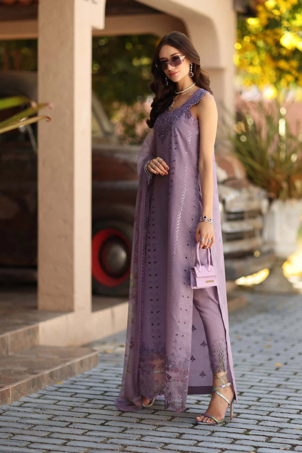 Woman in a long purple dress standing on a street.