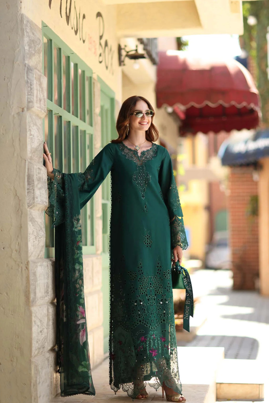 Woman in a long green dress standing on a street corner