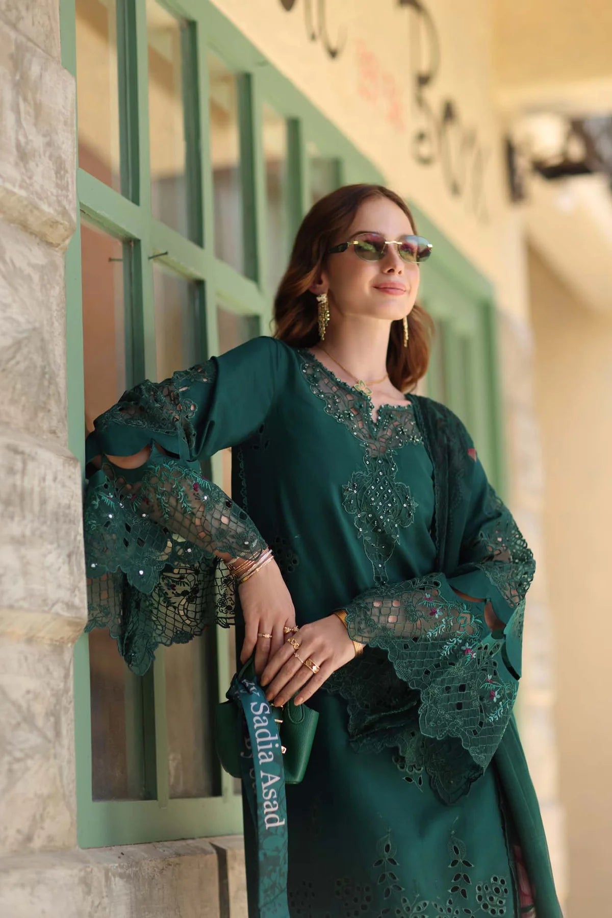 Woman in a green dress standing against a decorative wall