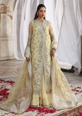 A woman models a traditional South Asian outfit featuring a light yellow-green (pistachio) embroidered kurta with a matching sheer dupatta, set against a draped white fabric background with scattered red rose petals on the floor.