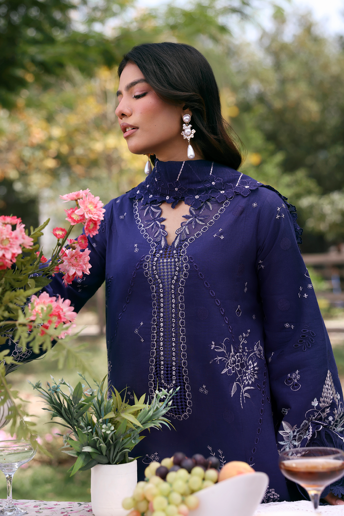 Woman in a blue embroidered dress holding flowers outdoors