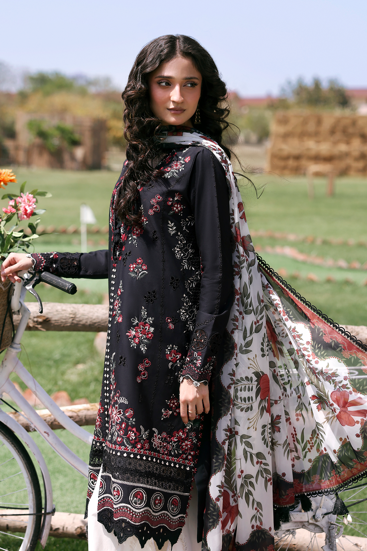 Woman in a floral dress with a bicycle and flowers in the background