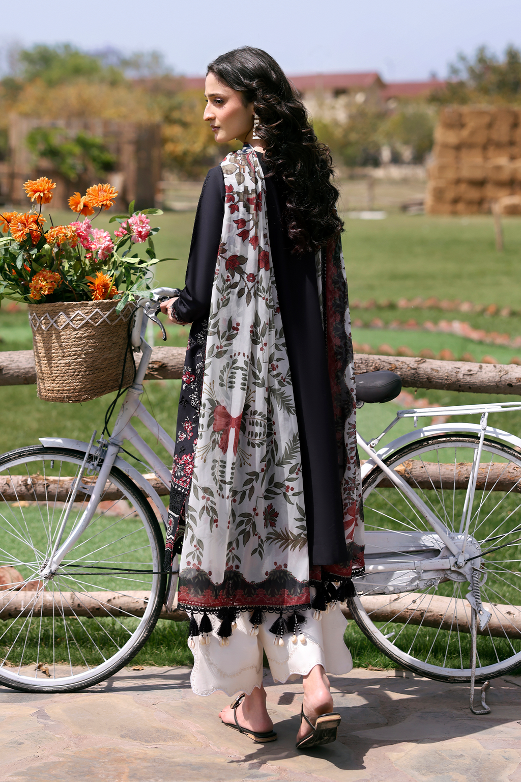 Woman in traditional attire with a bicycle and flowers in a field
