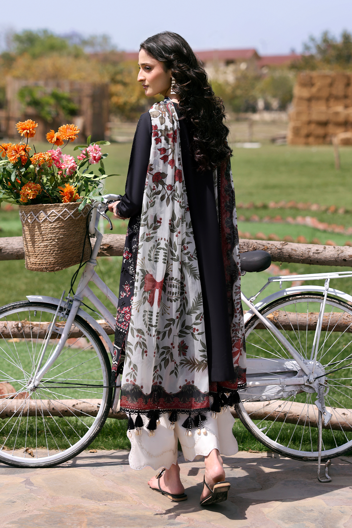 Woman in traditional attire with a bicycle and flowers in a field