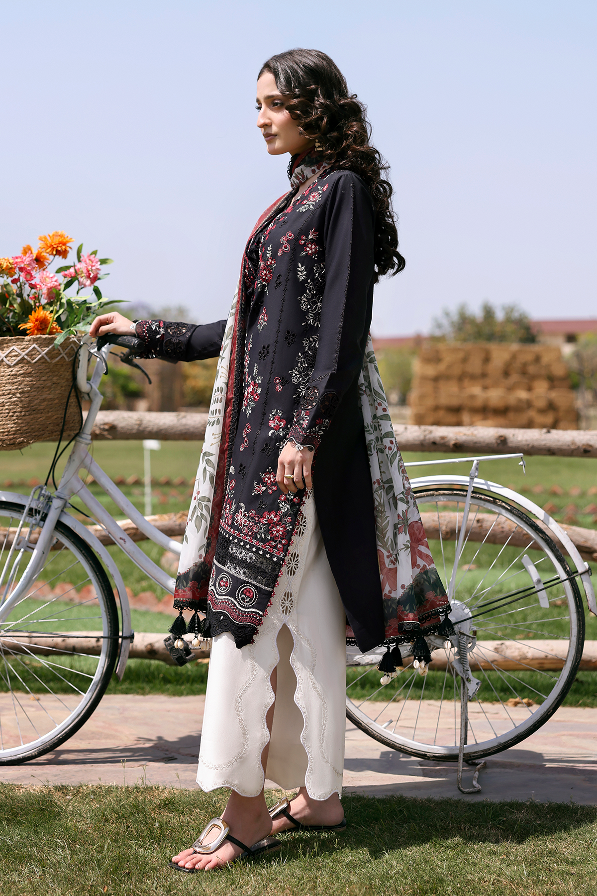 Woman in traditional outfit standing next to a bicycle with flowers in an outdoor setting