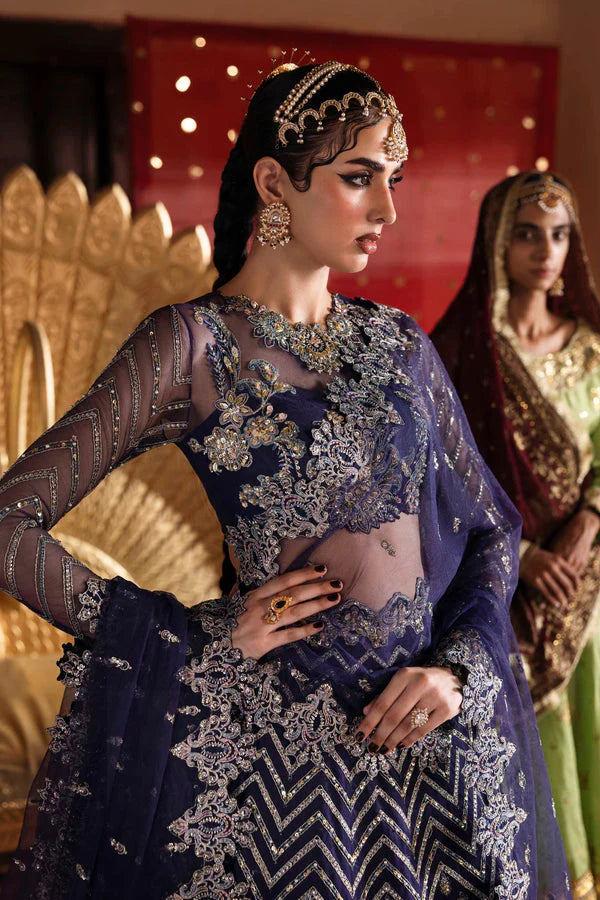 Woman in traditional embroidered outfit with another person in the background