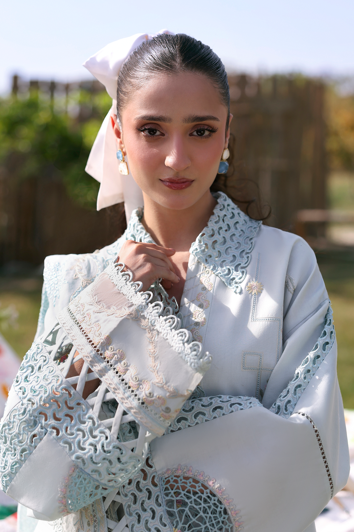 Woman in traditional attire with a decorative white shawl outdoors
