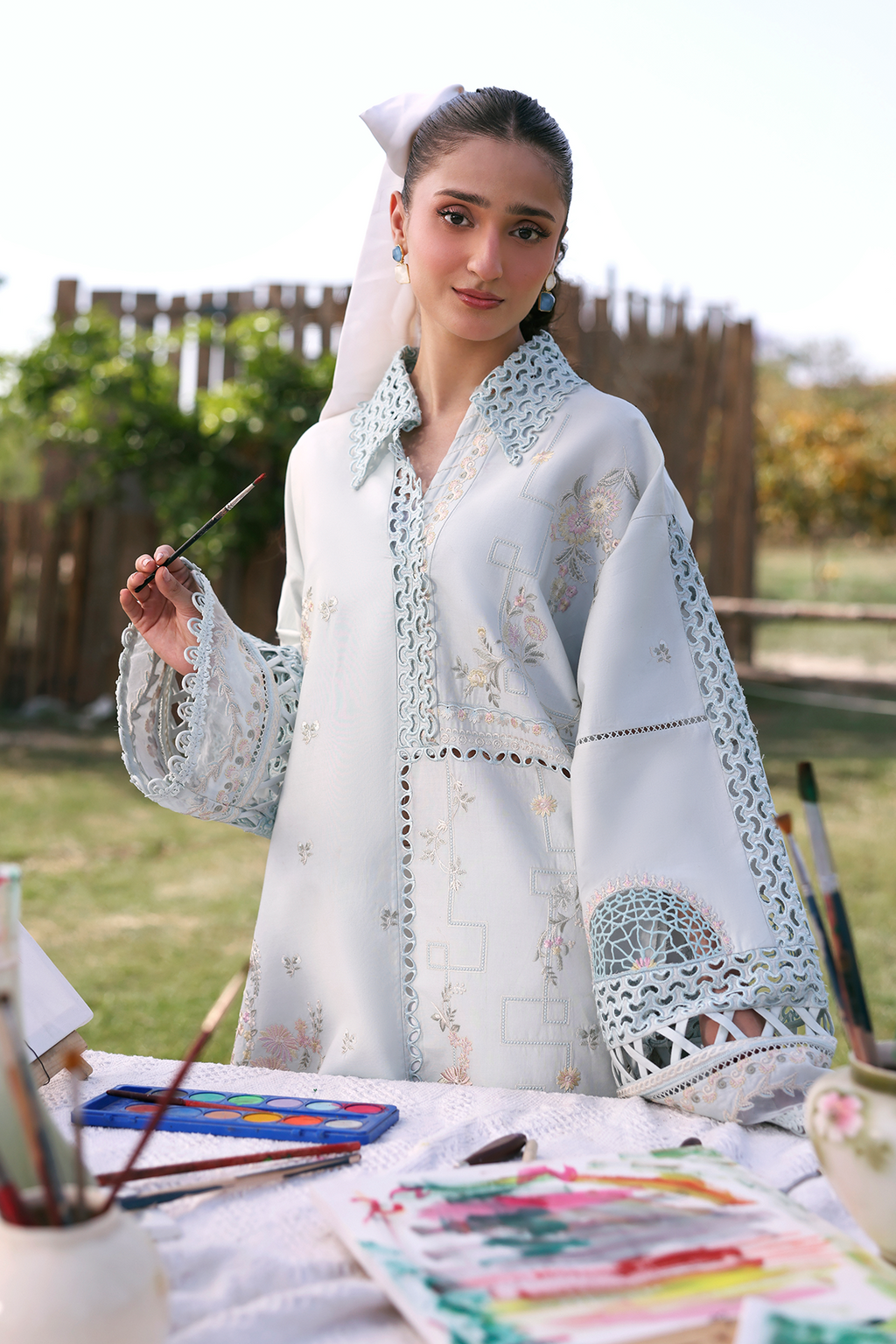 Woman in traditional embroidered outfit with art supplies outdoors