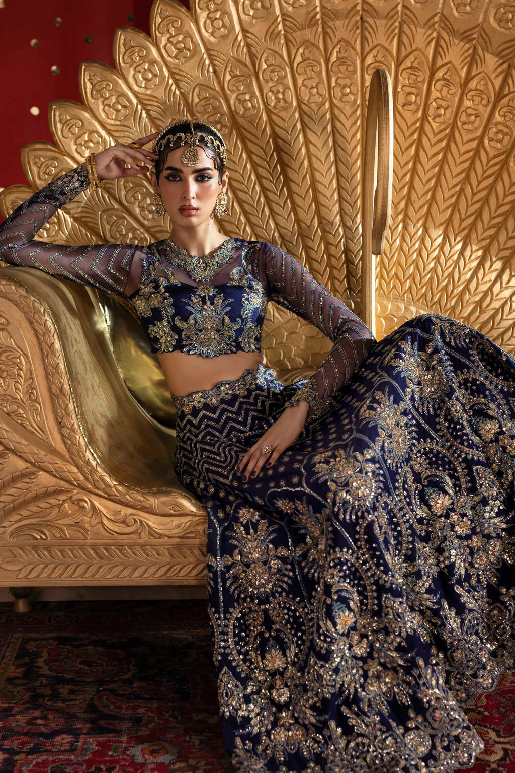 Woman in traditional attire sitting on a peacock-shaped chair.