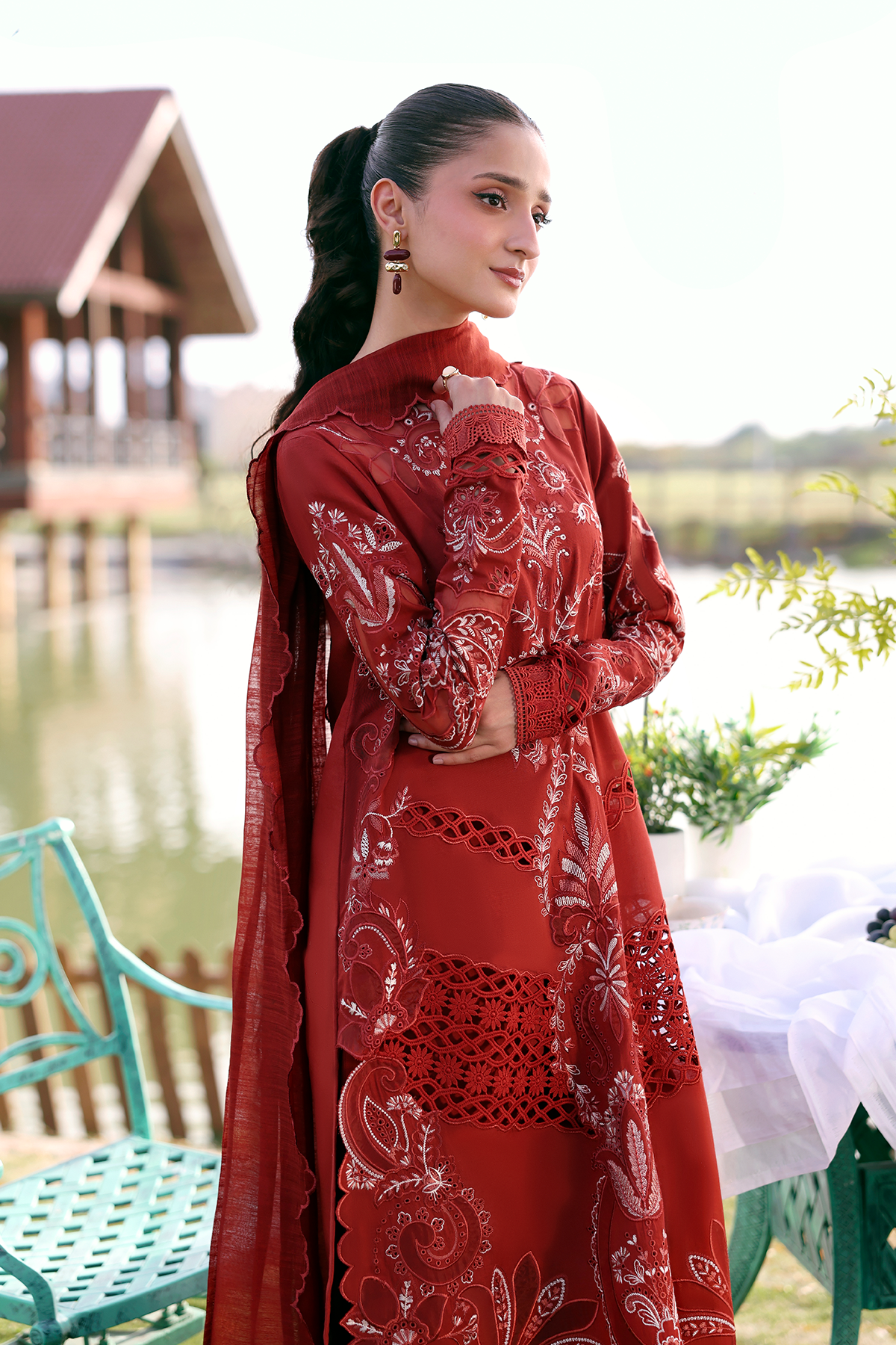 Woman in a red embroidered dress standing outdoors by a lake