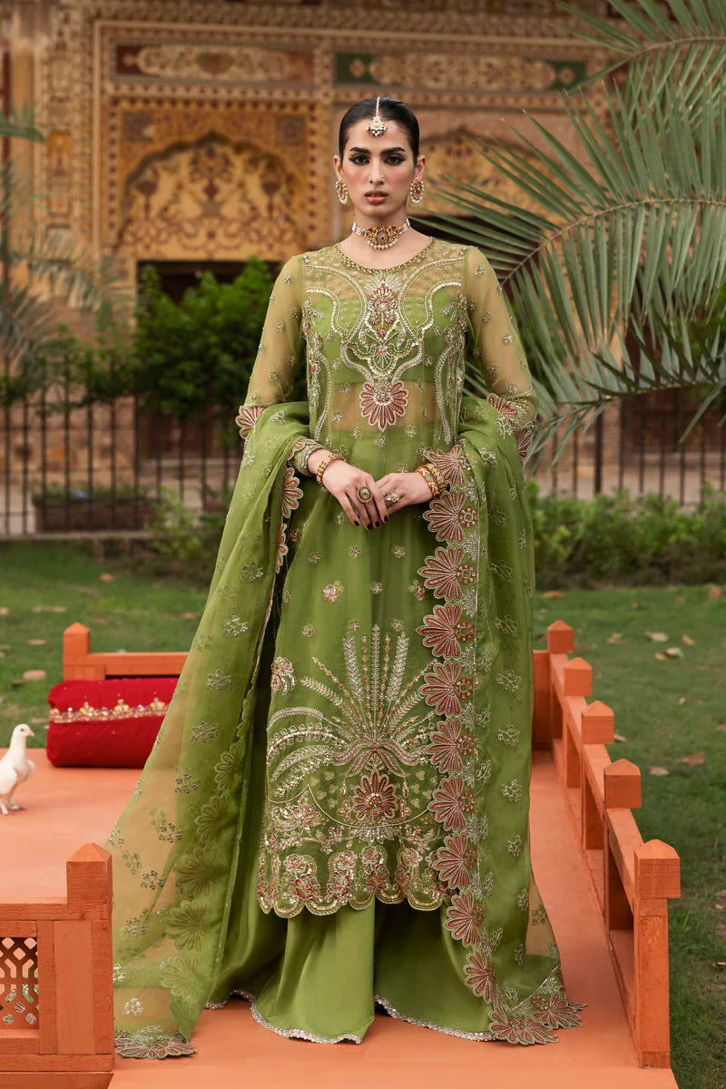 Woman in a green embroidered traditional outfit standing outdoors with decorative elements.