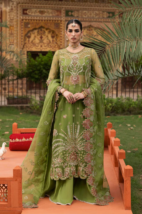 Woman in a green embroidered traditional outfit standing outdoors with decorative elements.
