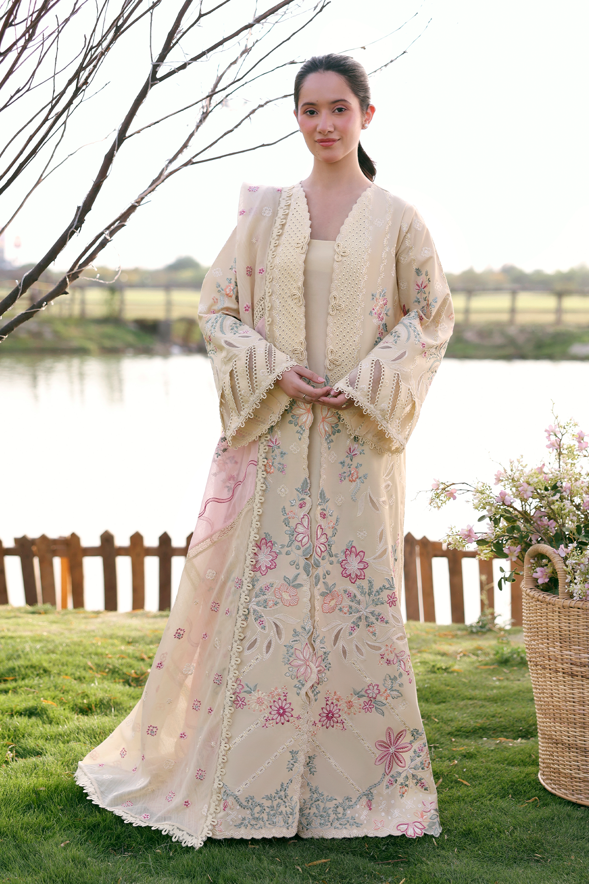 Woman in a floral dress standing outdoors by a lake