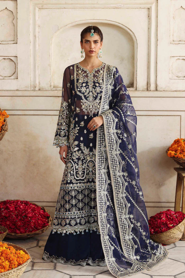 Woman in a traditional embroidered outfit standing in front of decorative elements.